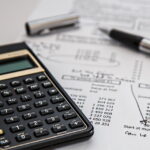 Calculadora e caneta fora do bocal sobre um extrato