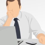 Homem sem expressão facial sentado em frente à mesa com computador e celular