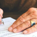 Mão assinando documento
