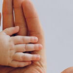 Mão de bebê sobre mão de adulto
